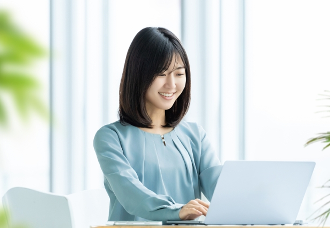 笑顔でpc作業する女性の写真
